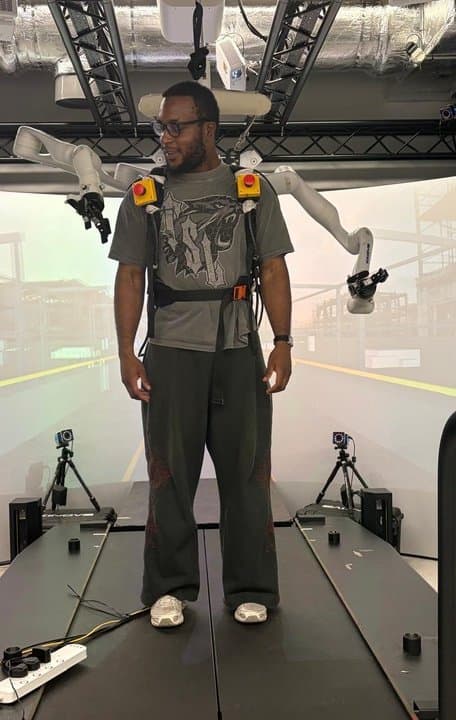 Christian wearing the dual-arm robot rig on a treadmill in the lab